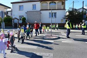 Policjanci kierują ruchem podczas akcji Kierowco, proszę zwolnij . Przedszkolaki przechodzą przez oznakowane przejście dla pieszych