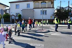 Policjanci kierują ruchem podczas akcji Kierowco, proszę zwolnij . Przedszkolaki przechodzą przez oznakowane przejście dla pieszych