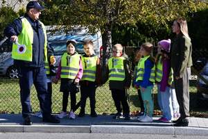 Policjant, opiekunka i przedszkolaki podczas akcji Kierowco,  proszę zwolnij