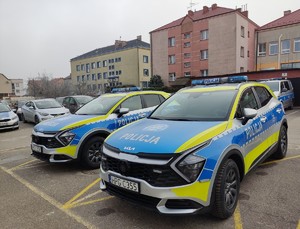 Dwa oznakowane radiowozy na parkingu Komendy Powiatowej Policji w  Dąbrowie Tarnowskiej
