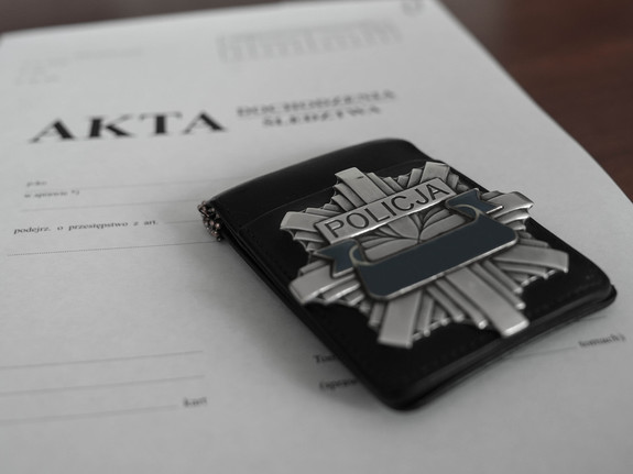Policyjna odznaka leżąca na teczce z aktami