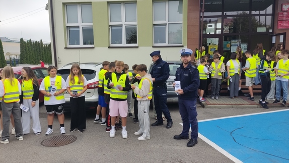 Policjanci rozdają dzieciom ulotki informacyjne