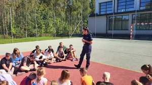 Policjantka prowadzi prelekcje dla uczniów na boisku szkolnym