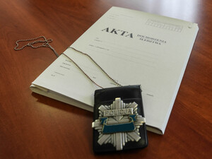 Teczka z aktami  sprawy, na której leży odznaka policyjna