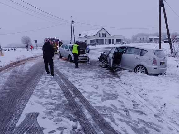 Kolizja dwóch samochodów osobowych, policjant i strażacy obsługują zdarzenie