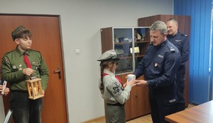 Harcerze przekazują Komendantowi Powiatowemu Policji w Dąbrowie Tarnowskiej Betlejemskie Wątło Pokoju