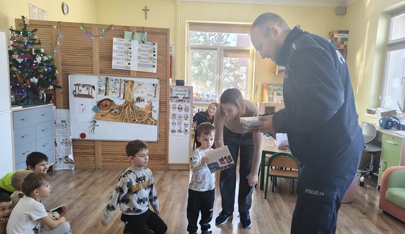 Policjant rozdaje ulotki przedszkolakom