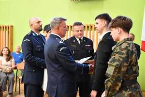 Policjanci wręczają listy gratulacyjne dwóm uczniom