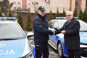 burmistrz Dąbrowy Tarnowskiej przekazuje kluczyki do radiowozu Naczelnikowi Wydziału Prewencji i Ruchu Drogowego w tle oznakowane radiowozy toyota