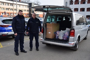 Zdjęcie przedstawia dwóch umundurowanych policjantów chwilę po załadowaniu bagażnika z darami tj. pluszakami dla dzieci z Ukrainy.