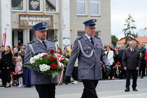 komendanci ubrami w mundury galowe składają wiązanki kwiatów