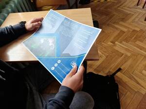 uczeń trzymający ulotkę zachęcającą do służy w Policji w ławce szkolnej