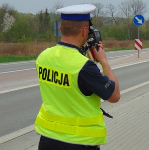 umundurowany policjant mierzący prędkość urządzeniem pomiarowym